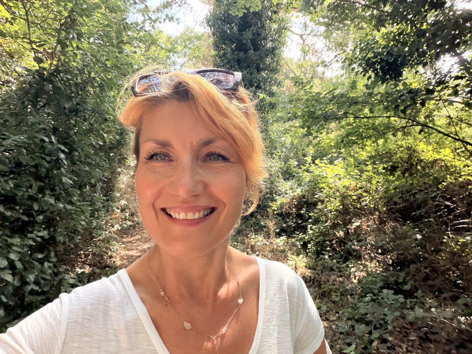 Julia smiling on a sunlit woodland path